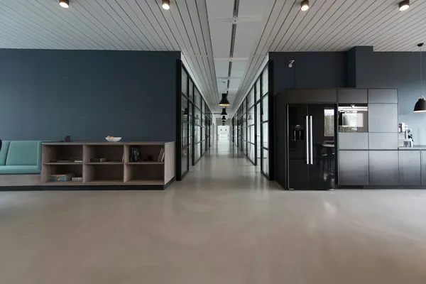A contemporary workspace with glass partitions and a long central corridor